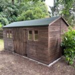 Traditional dark wood apex garden shed with double doors and four windows, installed on a level concrete base in Harlow.