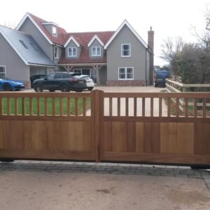 Modern bespoke Iroko hardwood driveway gates featuring integrated vision panels, handcrafted in our Hertfordshire workshop and installed for an Essex property.