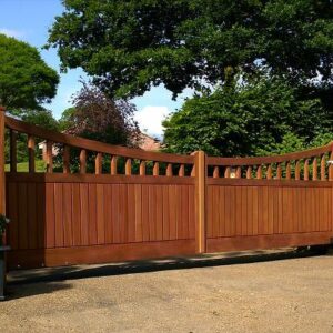 Bespoke handcrafted dipping hardwood driveway gates featuring an integrated vision panel, manufactured in our Hertfordshire workshop for a local installation.