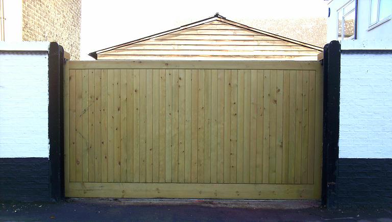A bespoke workshop-manufactured softwood vertical tongue and groove sliding driveway gate set up for manual or automated opening in Harlow.